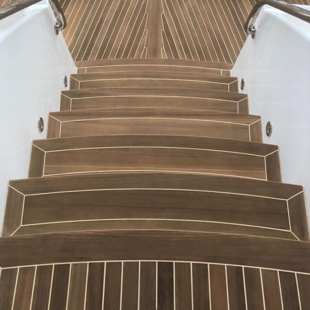 Image of white caulking and teak steps descending from one teak deck to another level of decking